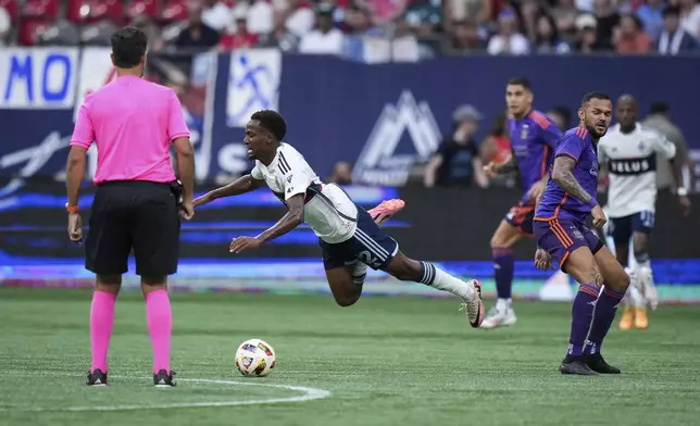 Vancouver Whitecaps' Ali Ahmed, center, is upended by Houston Dynamo's Artur, front right, in front of referee Fotis Bazakos, left, during the first half of an MLS soccer match in Vancouver, British Columbia, Saturday, July 20, 2024. (Darryl Dyck/The Canadian Press via AP)