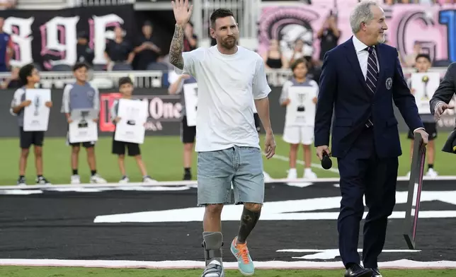 Inter Miami forward Lionel Messi, left, waves as he walks off the field with team managing owner Jorge Mas after being honored for his 45 career trophies before an MLS soccer match against the Chicago Fire, Saturday, July 20, 2024, in Fort Lauderdale, Fla. (AP Photo/Lynne Sladky)