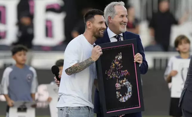 Inter Miami forward Lionel Messi, left, stands with team managing owner Jorge Mas as Messi is awarded for his 45 career trophies before an MLS soccer match against the Chicago Fire, Saturday, July 20, 2024, in Fort Lauderdale, Fla. (AP Photo/Lynne Sladky)