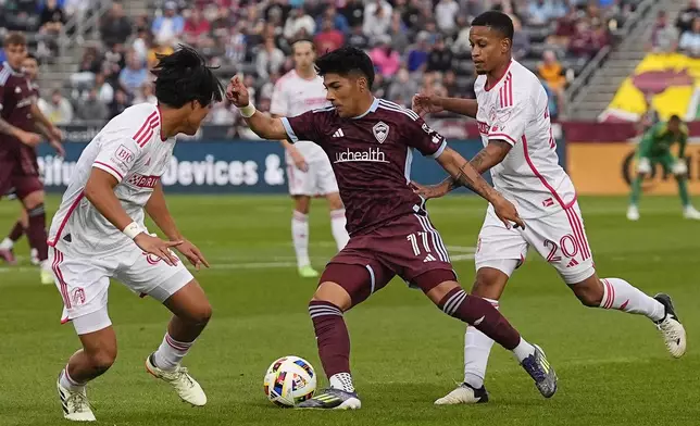 Colorado Rapids midfielder Omir Fernandez, center, drives between St. Louis City midfielder Hosei Kijima, left, and defender Akil Watts in the first half of a MLS soccer match Sunday, July 7, 2024, in Commerce City, Colo. (AP Photo/David Zalubowski)