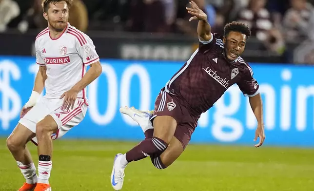 Colorado Rapids forward Jonathan Lewis, right, flies after tripping over the foot of St. Louis City midfielder Indiana Vassilev in the second half of a MLS soccer match Sunday, July 7, 2024, in Commerce City, Colo. (AP Photo/David Zalubowski)