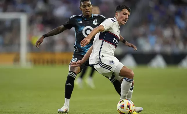 Vancouver Whitecaps midfielder Alessandro Schopf, right, and Minnesota United midfielder Joseph Rosales battle for possession of the ball during the second half of an MLS soccer match in St. Paul, Minn., Wednesday, July 3, 2024. (AP Photo/Abbie Parr)
