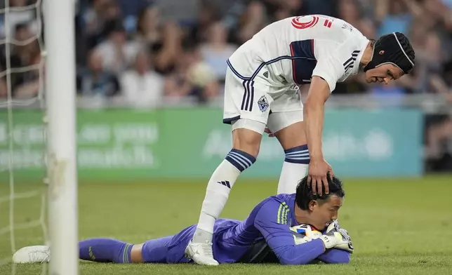 Vancouver Whitecaps goalkeeper Yohei Takaoka, bottom, is acknowledged by defender Bjorn Inge Utvik after stopping a shot during the second half of an MLS soccer match against Minnesota United in St. Paul, Minn., Wednesday, July 3, 2024. (AP Photo/Abbie Parr)