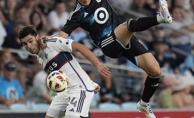 Vancouver Whitecaps forward Brian White, left, and Minnesota United defender Miguel Tapias battle for possession of the ball during the second half of an MLS soccer match in St. Paul, Minn., Wednesday, July 3, 2024. (AP Photo/Abbie Parr)