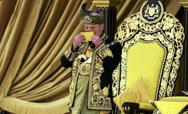 The 17th King of Malaysia, Sultan Ibrahim Iskandar, left, kisses a copy of the Quran during his coronation at the National Palace in Kuala Lumpur, Malaysia, Saturday, July 20, 2024. (Hasnoor Hussain/Pool Photo via AP)