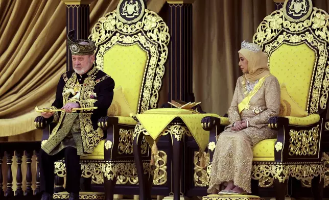 The 17th King of Malaysia, Sultan Ibrahim Iskandar, left, lifts a ceremonial dagger as Queen Raja Zarith Sofiah looks on during his coronation at the National Palace in Kuala Lumpur, Malaysia, Saturday, July 20, 2024. (Hasnoor Hussain/Pool Photo via AP)