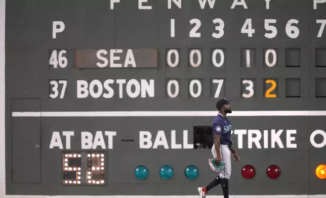 Seattle Mariners left fielder Randy Arozarena walks past the Green Monster scoreboard during the fifth inning of a baseball game against the Boston Red Sox, Monday, July 29, 2024, in Boston. (AP Photo/Charles Krupa)