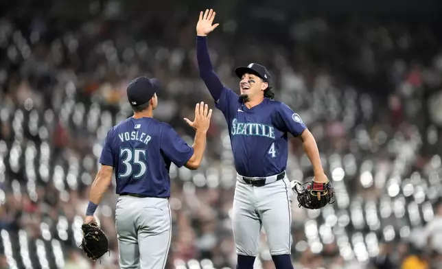 The Seattle Mariners' Jason Vosler (35) and Josh Rojas celebrate their shutout of the Chicago White Sox in a baseball game Friday, July 26, 2024, in Chicago. (AP Photo/Charles Rex Arbogast)