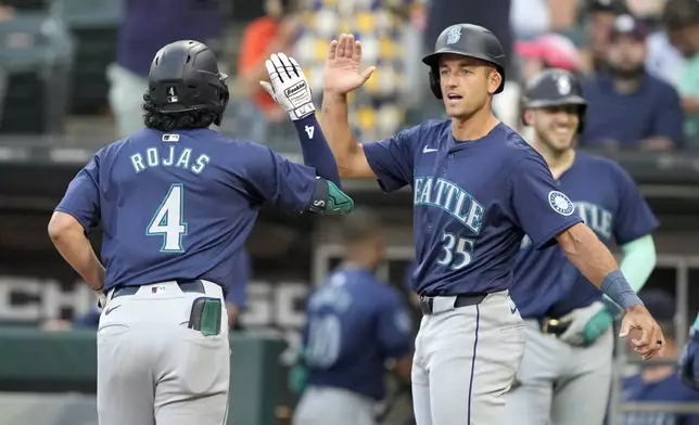 Seattle Mariners' Jason Vosler (35) greets Josh Rojas (4) at home after Rojas' three-run home run off Chicago White Sox starting pitcher Drew Thorpe in the first inning of a baseball game Friday, July 26, 2024, in Chicago. (AP Photo/Charles Rex Arbogast)