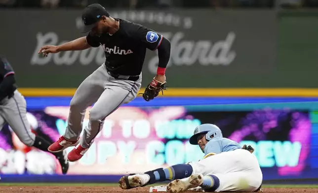 Miami Marlins' Otto Lopez, front left, jumps up after tagging out Milwaukee Brewers' Blake Perkins, right, at second base during the fifth inning of a baseball game Friday, July 26, 2024, in Milwaukee. (AP Photo/Aaron Gash)