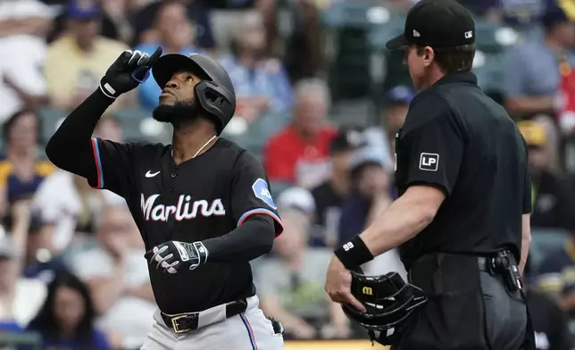 Miami Marlins' Bryan De La Cruz, left, gestures after hitting a two-run home run during the first inning of a baseball game against the Milwaukee Brewers, Friday, July 26, 2024, in Milwaukee. (AP Photo/Aaron Gash)