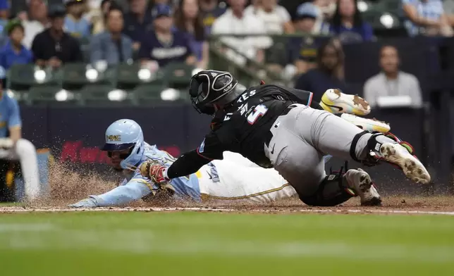 Milwaukee Brewers' William Contreras, left, slides safely into home past the tag of Miami Marlins' Nick Fortes, right, to score on a sacrifice fly hit by Gary Sánchez during the fourth inning of a baseball game Friday, July 26, 2024, in Milwaukee. (AP Photo/Aaron Gash)