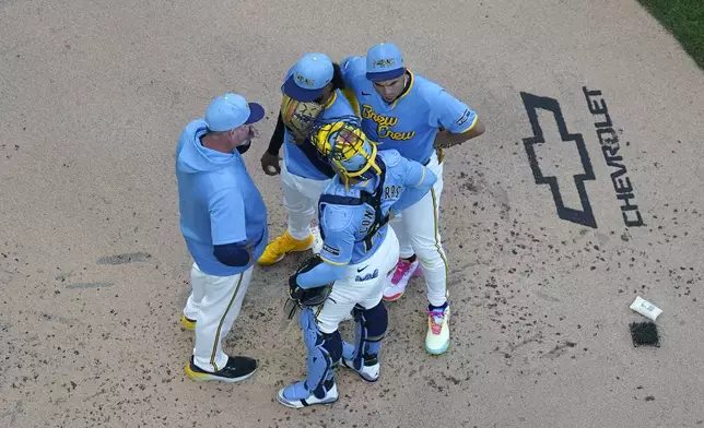 Milwaukee Brewers' Freddy Peralta, top center, meets on the mound with pitching coach Chris Hook, left, and teammates during the second inning of a baseball game against the Miami Marlins, Friday, July 26, 2024, in Milwaukee. (AP Photo/Aaron Gash)