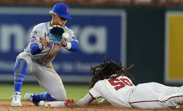 Washington Nationals' James Wood, right, slides into second base ahead of a throw to New York Mets shortstop Francisco Lindor, left, during the ninth inning of a baseball game at Nationals Park, Monday, July 1, 2024, in Washington. (AP Photo/Mark Schiefelbein)