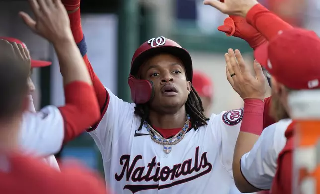 Washington Nationals' CJ Abrams celebrates with teammates after scoring during the third inning of a baseball game against the New York Mets at Nationals Park, Monday, July 1, 2024, in Washington. (AP Photo/Mark Schiefelbein)
