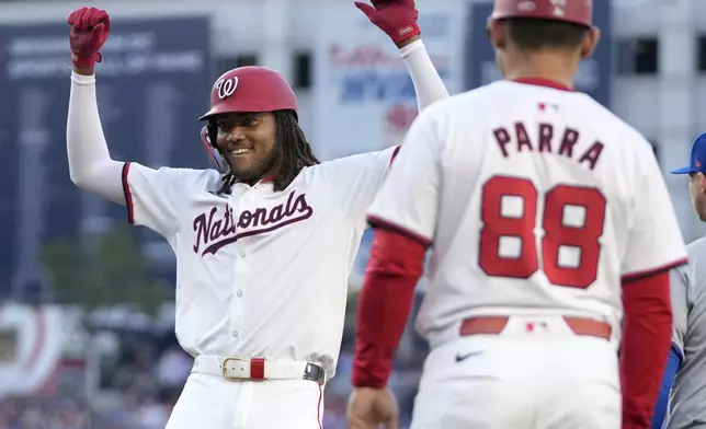 Washington Nationals' James Wood, left, reacts after notching a base hit in his first major league at-bat during the second inning of a baseball game against the New York Mets at Nationals Park, Monday, July 1, 2024, in Washington. (AP Photo/Mark Schiefelbein)