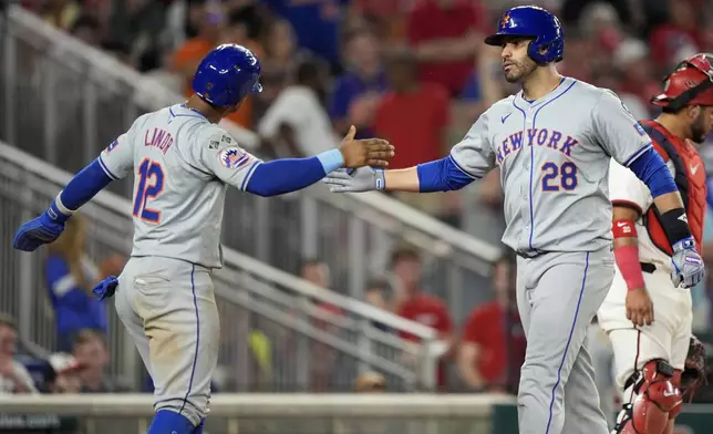 New York Mets' J.D. Martinez (28) is congratulated by teammate Francisco Lindor (12) after hitting a three-run home run during the 10th inning of a baseball game against the Washington Nationals at Nationals Park, Monday, July 1, 2024, in Washington. (AP Photo/Mark Schiefelbein)