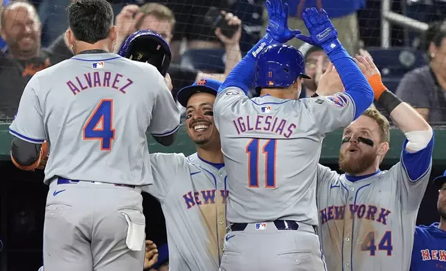 New York Mets' Mark Vientos, second from left, and Harrison Bader (44) celebrate with Francisco Alvarez (4) and Jose Iglesias (11) after Iglesias hit a two-run home run during the 10th inning of a baseball game at Nationals Park, Monday, July 1, 2024, in Washington. (AP Photo/Mark Schiefelbein)