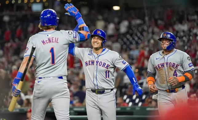 New York Mets' Jose Iglesias, center, celebrates after his two-run home run with Jeff McNeil, left, and Francisco Alvarez, right, during the 10th inning of a baseball game against the Washington Nationals at Nationals Park, Monday, July 1, 2024, in Washington. (AP Photo/Alex Brandon)