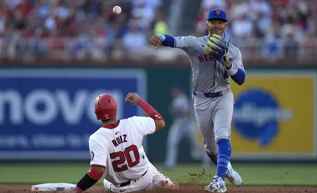 New York Mets shortstop Francisco Lindor, right, throws to first base after forcing out Washington Nationals' Keibert Ruiz (20) at second base during the second inning of a baseball game at Nationals Park, Monday, July 1, 2024, in Washington. (AP Photo/Mark Schiefelbein)