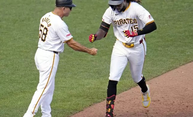 Pittsburgh Pirates' Oneil Cruz (15) rounds third to greetings from third base coach Mike Rabelo, left, after hitting a two-run home run off New York Mets starting pitcher David Peterson during the fourth inning of a baseball game in Pittsburgh, Saturday, July 6, 2024. (AP Photo/Gene J. Puskar)