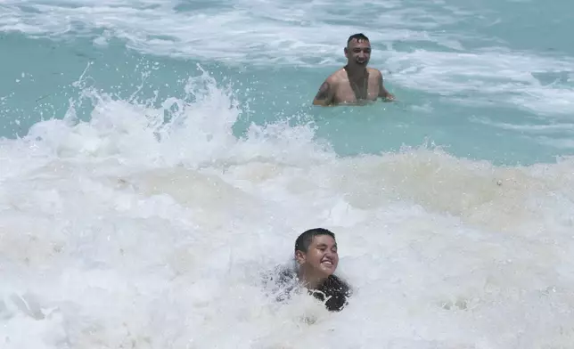 Tourists swim in the ocean ahead of Hurricane Beryl's expected arrival in Cancun, Mexico, Wednesday, July 3, 2024. (AP Photo/Fernando Llano)
