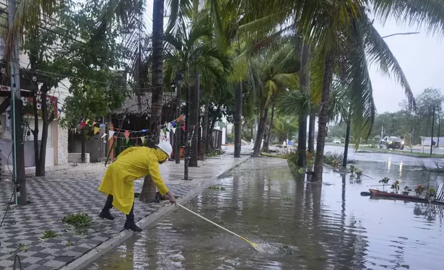 A man unclogs a drain in the aftermath of Hurricane Beryl, in Tulum, Mexico, Friday, July 5, 2024. (AP Photo/Fernando Llano)