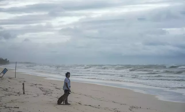 A man and his dog stand on the shore of a beach in the aftermath of Hurricane Beryl in Tulum, Mexico, Friday, July 5, 2024. (AP Photo/Fernando Llano)