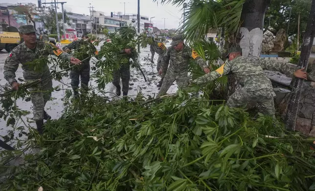 Soldiers collect branches felled by Hurricane Beryl, in Tulum, Mexico, Friday, July 5, 2024. (AP Photo/Fernando Llano)