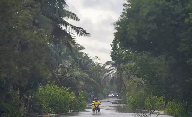 A motorcyclist rides throw a street flooded by heavy rains from Hurricane Beryl, in Tulum, Mexico, Friday, July 5, 2024. (AP Photo/Fernando Llano)