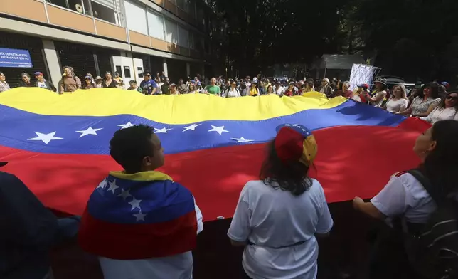 Venezuelans living in Mexico hold a Venezuelan flag outside their nation's embassy that has a polling station set up for the presidential election in Mexico City, Sunday, July 28, 2024. (AP Photo/Ginnette Riquelme)