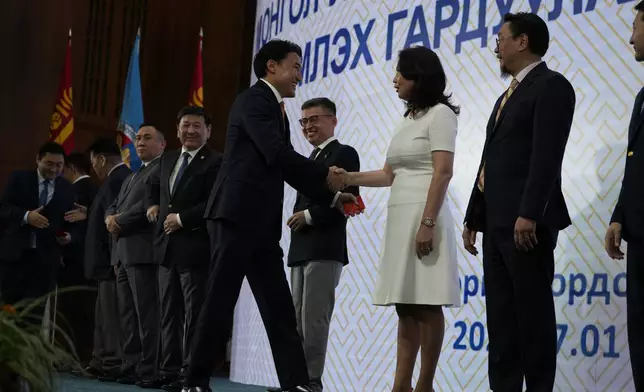 Ruling Mongolian People's Party lawmaker Damdinnyam Gongor is congratulated on stage upon receiving his Parliamentary membership card handed out to newly elected lawmakers at the Mongolian Government Palace in Ulaanbaatar, Mongolia, Monday, July 1, 2024. (AP Photo/Ng Han Guan)