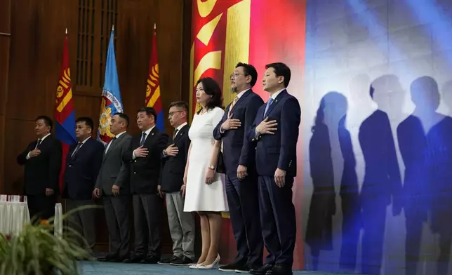 Attendees stand for the anthem during a ceremony to handout Parliamentary membership cards to newly elected lawmakers at the Mongolian Government Palace in Ulaanbaatar, Mongolia, Monday, July 1, 2024. (AP Photo/Ng Han Guan)
