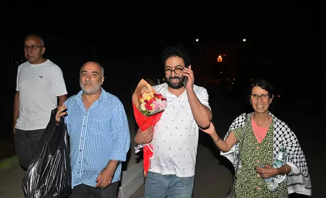 Omar Radi, a journalist and activist, second from right, speaks on the phone after he was pardoned and released from prison in Tifelt, Morocco, Monday, July 29, 2024. Morocco's King Mohammed VI on Monday pardoned a group of journalists who were charged with sex crimes and espionage in prosecutions widely condemned by press freedom advocates as retaliatory in response to critical reporting. (AP Photo)