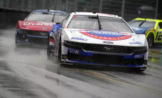 Brad Keselowski and other drivers are forced to go at a slower pace as rain falls during a NASCAR Cup Series auto race, Sunday, July 7, 2024, in Chicago. (AP Photo/Erin Hooley)