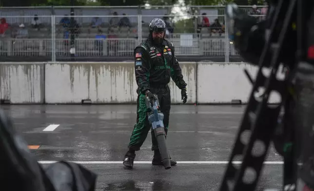 One of Austin Dillon's pit crew members blows rainwater off the ground during a NASCAR Cup Series auto race, Sunday, July 7, 2024, in Chicago. (AP Photo/Erin Hooley)