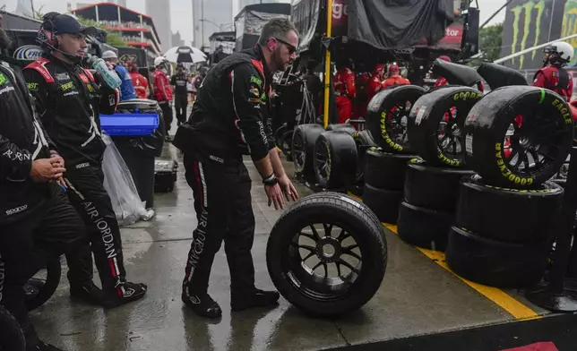 Tyler Reddick's pit crew rolls out new tires as rain falls during a NASCAR Cup Series auto race, Sunday, July 7, 2024, in Chicago. (AP Photo/Erin Hooley)