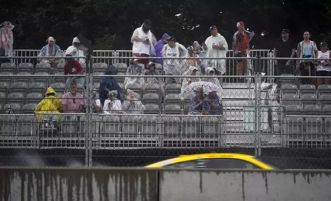 Fans try to stay dry as rain pours down during a NASCAR Cup Series auto race, Sunday, July 7, 2024, in Chicago. (AP Photo/Erin Hooley)