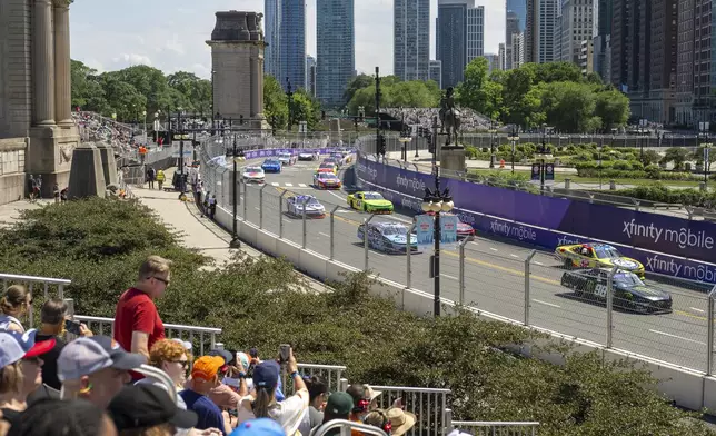 Fans watch as vehicles drive along Turn 19 during a NASCAR Xfinity Series street course auto race in Grant Park in Chicago, Saturday, July 6, 2024. (Tyler Pasciak LaRiviere/Chicago Sun-Times via AP)