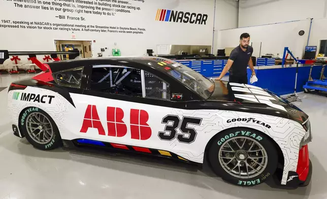 CJ Tobin, senior engineer of vehicle systems, cleans a prototype of the first electric racecar at the NASCAR R&amp;D Center in Concord, N.C., Monday, July 1, 2024. The top motorsports series in North America partnered with Chevrolet, Ford, Toyota and electrification company ABB to demonstrate a high-performance electric vehicle and gauge fan interest in electric racing. (AP Photo/Nell Redmond)