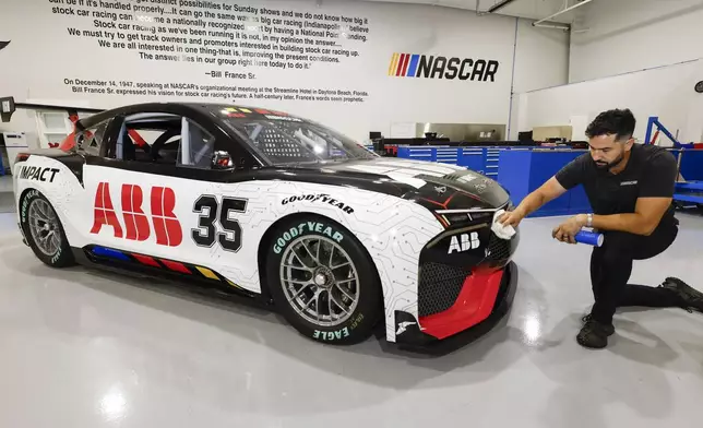 CJ Tobin, senior engineer of vehicle systems, cleans a prototype of the first electric racecar at the NASCAR R&amp;D Center in Concord, N.C., Monday, July 1, 2024. The top motorsports series in North America partnered with Chevrolet, Ford, Toyota and electrification company ABB to demonstrate a high-performance electric vehicle and gauge fan interest in electric racing. (AP Photo/Nell Redmond)