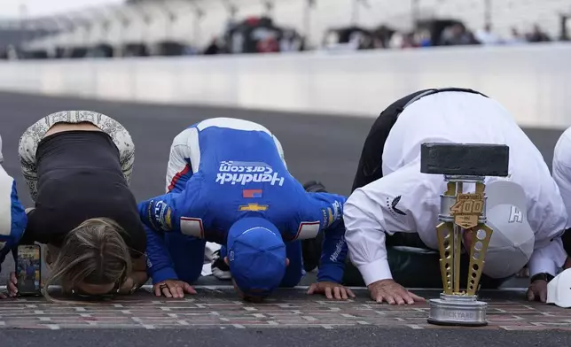 From left to right, Katelyn Larson, Kyle Larson and Rick Hendrick kiss the bricks after Kyle won a NASCAR Cup Series auto race at Indianapolis Motor Speedway, Sunday, July 21, 2024, in Indianapolis. (AP Photo/Darron Cummings)