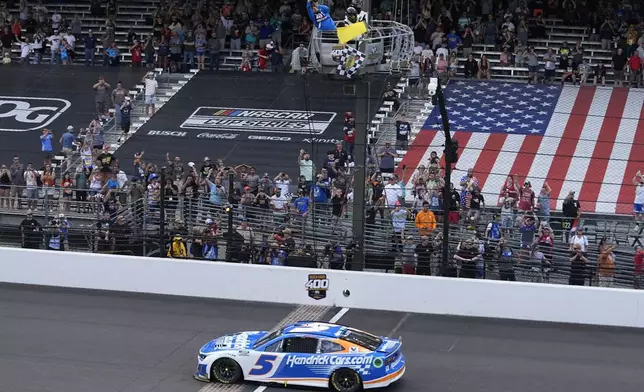 Kyle Larson takes the checkered flag to win a NASCAR Cup Series auto race at Indianapolis Motor Speedway, Sunday, July 21, 2024, in Indianapolis. (AP Photo/Darron Cummings)