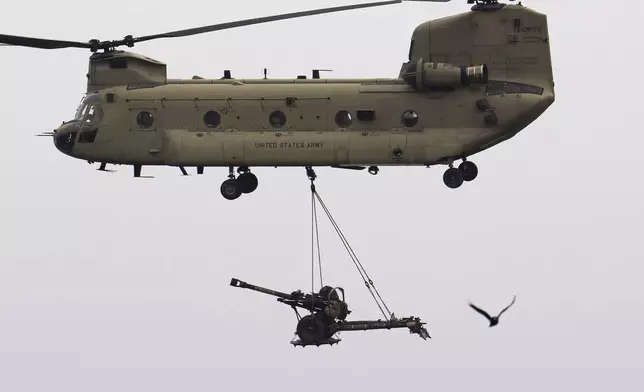 FILE - A transport helicopter carries an artilery piece of the United States 101 Airborne Division run during an exercise at the Mihail Kogalniceanu Air Base, near the Black Sea port of Constanta, Romania, on March 31, 2023. Trump's threat to renege on NATO's collective security guarantee, a cornerstone of the alliance, is based on his belief that member states aren't living up to their funding commitments, forcing U.S. taxpayers to subsidize Europe's defense. (AP Photo/Vadim Ghirda, File)