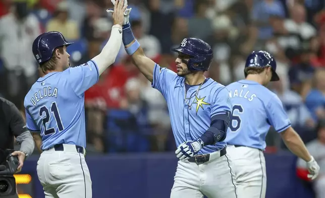 Tampa Bay Rays' Jonny DeLuca, left, congratulates Jose Caballero, center, who hit a two-run home run against the Washington Nationals during the second inning of a baseball game Sunday, June 30, 2024, in St. Petersburg, Fla. (AP Photo/Mike Carlson)