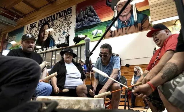 Mark Erickson, third from left, leads others in singing on the drum during an open drum and dance night at Minneapolis American Indian Center on Wednesday, July 10, 2024, in Minneapolis, Minn. (AP Photo/Mark Vancleave)