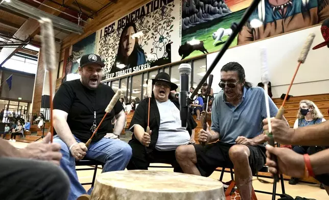 Mark Erickson, third from left, leads others in singing on the drum during an open drum and dance night at Minneapolis American Indian Center on Wednesday, July 10, 2024, in Minneapolis, Minn. (AP Photo/Mark Vancleave)