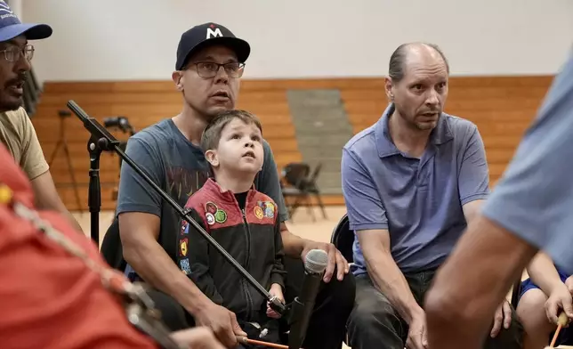 Nation Wright Sr. and his son Niigaanii sing on the drum during an open drum and dance night at Minneapolis American Indian Center on Wednesday, July 10, 2024, in Minneapolis, Minn. (AP Photo/Mark Vancleave)