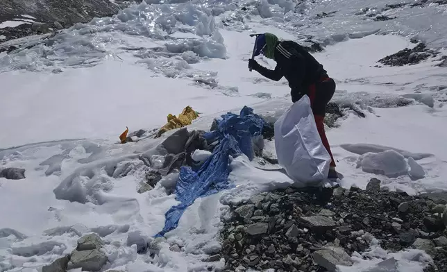 This image provided by the Peak Promotion shows a member of the Nepal government-funded team using a spade to remove frozen trash en route the Mount Everest, Nepal, Tuesday, April 27, 2021. In the seven decades since Mount Everest was first conquered, thousands of climbers have scaled the peak, and many have left behind more than just their footprints. Tons of trash and several bodies remain on the icy slopes of the world's highest mountain. (Peak Promotion via AP)