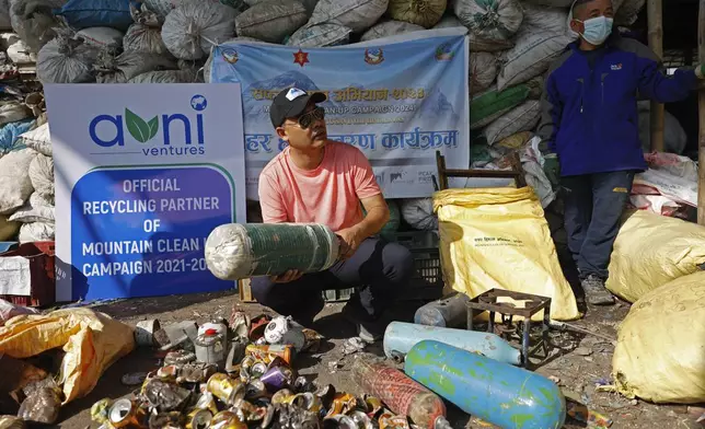 Sushil Khadga of the Agni Ventures, an agency that manages recyclable waste, checks an used oxygen cylinder collected en route Mount Everest before it is recycled at the facility, in Kathmandu, Nepal, Monday, June 24, 2024. The highest camp on the world's tallest mountain is littered with garbage that is going to take years to clean up, according to a Sherpa who led a team that worked to clear trash and dig up dead bodies frozen for years near Mount Everest's peak. (AP Photo/Sanjog Manandhar)